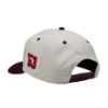 Left side view of "The Heritage Snapback", showing cream paneling with a burgundy "53" detail and snapback closure.