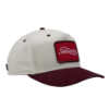 Two-tone view of "The Heritage Snapback", showing a cream crown, burgundy brim, and red front patch logo.