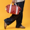 Sargento Cheeseburger Cooler Bag carried by hand, showing red cheeseburger pattern and white straps